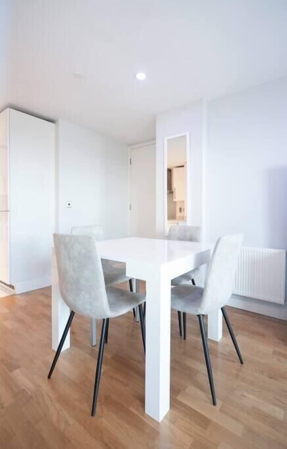 A modern living room on the 12th floor features a 60-inch TV, a dining table with four chairs, and access to a balcony with stunning city views. Two electric reclined sofas provide comfort and a sound system offer entertainment.