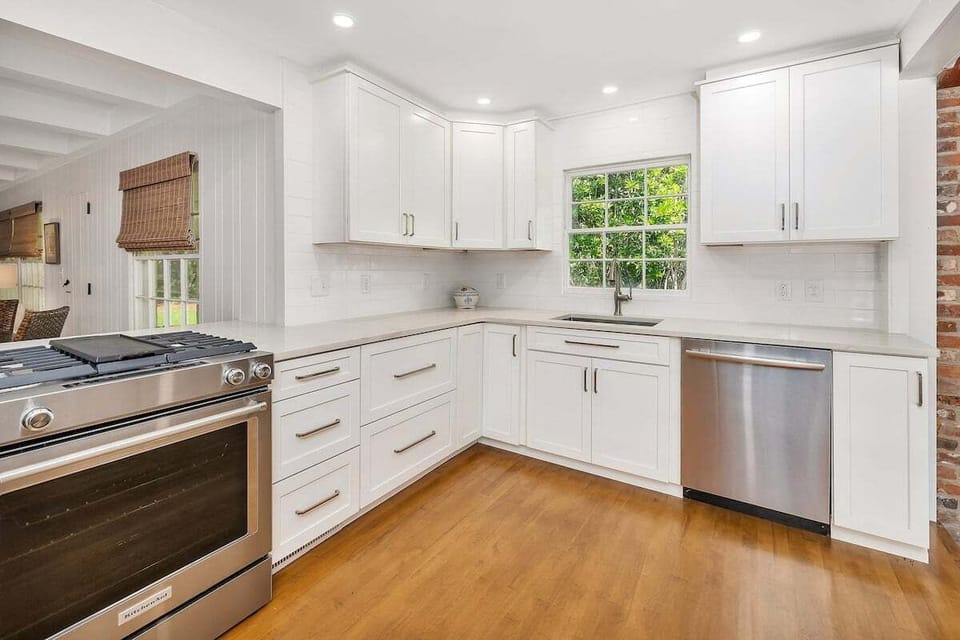 White kitchen with stainless range, dishwasher, and window