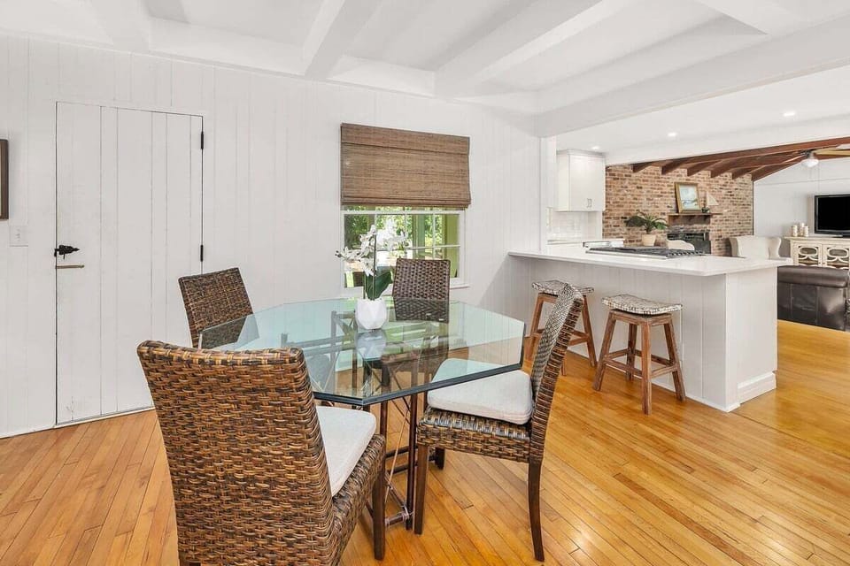 Dining area with wicker chairs and white kitchen beyond