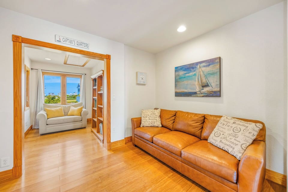 Settle into this inviting lounge with rich leather seating and warm wood floors. Through the doorway, discover your cozy Captain's Quarters reading nook, where ocean views frame peaceful moments.