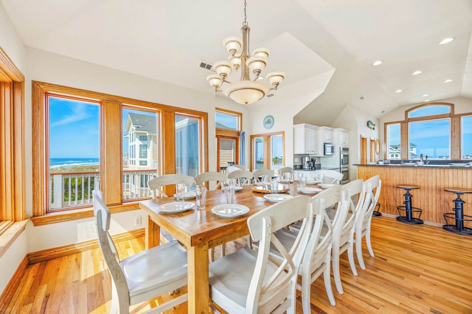 Gather around the sun-drenched dining table where warm wood meets coastal views, inviting you to share memorable meals with loved ones in this light-filled, open-concept space.