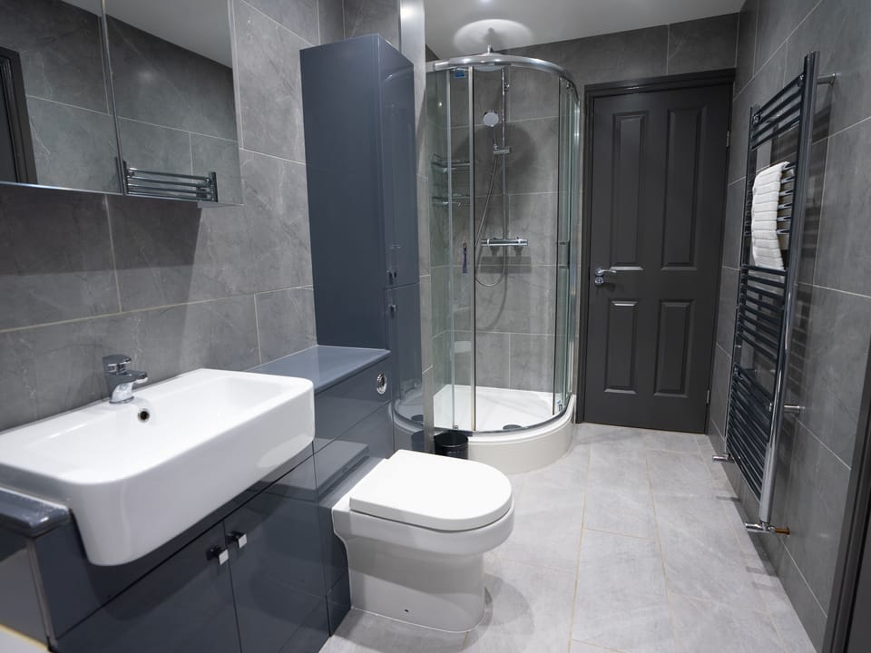 The enclosed shower area, stylish fixtures, such as a rainfall showerhead and coordinating tiles, enhance the overall ambiance.
