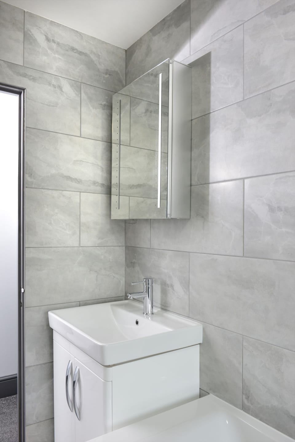  Our modern bathroom features a sleek white sink and a stylish hanging glass cabinet, adding a touch of sophistication to your stay.