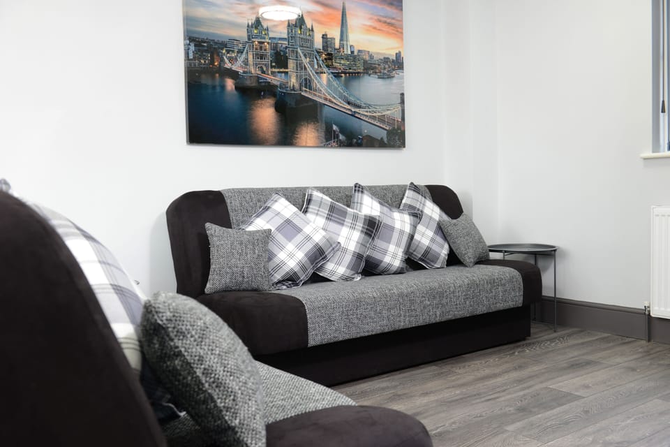 Sophistication in your living room! Featuring a plush gray sofa, chic chequered throw pillows, and a captivating hanging painting that adds a touch of elegance to your stay.