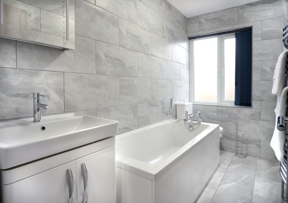 Bathe in luxury in our modern and elegant bathroom, featuring a pristine white tub that invites you to relax and unwind in style."