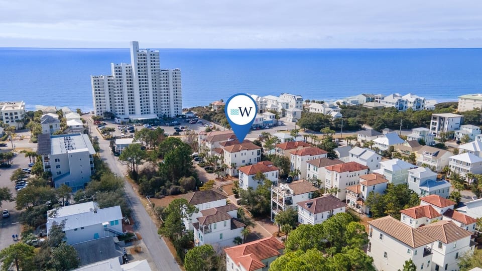 Aerial view of a coastal residential community with nearby high-rise buildings and beautiful oceanfront location.