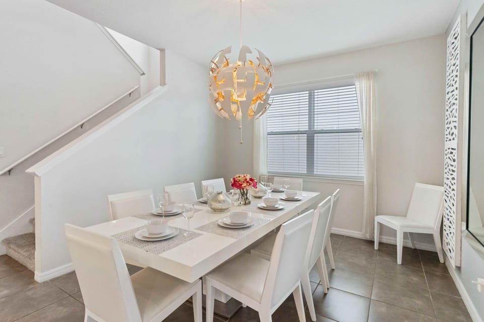 Swish dining area of the home in Kissimmee Florida - An eight seater dining table  - An extra chair for a more comfortable space - Statement chandelier - Quality materials, such as a sleek dining table and comfortable chairs