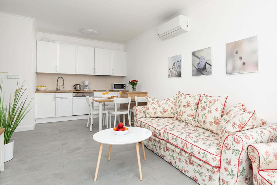 Air-conditioned living room with a sofa bed, TV and kitchenette with dining area.