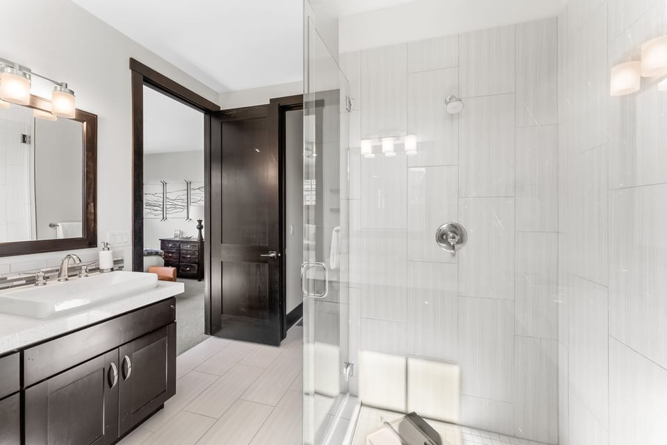 - Refresh in a modern bathroom with glass shower and sleek tile walls  
- Large vanity and bright mirror lighting provide convenience daily  
- Easy access connects the bathroom directly to the bedroom suite