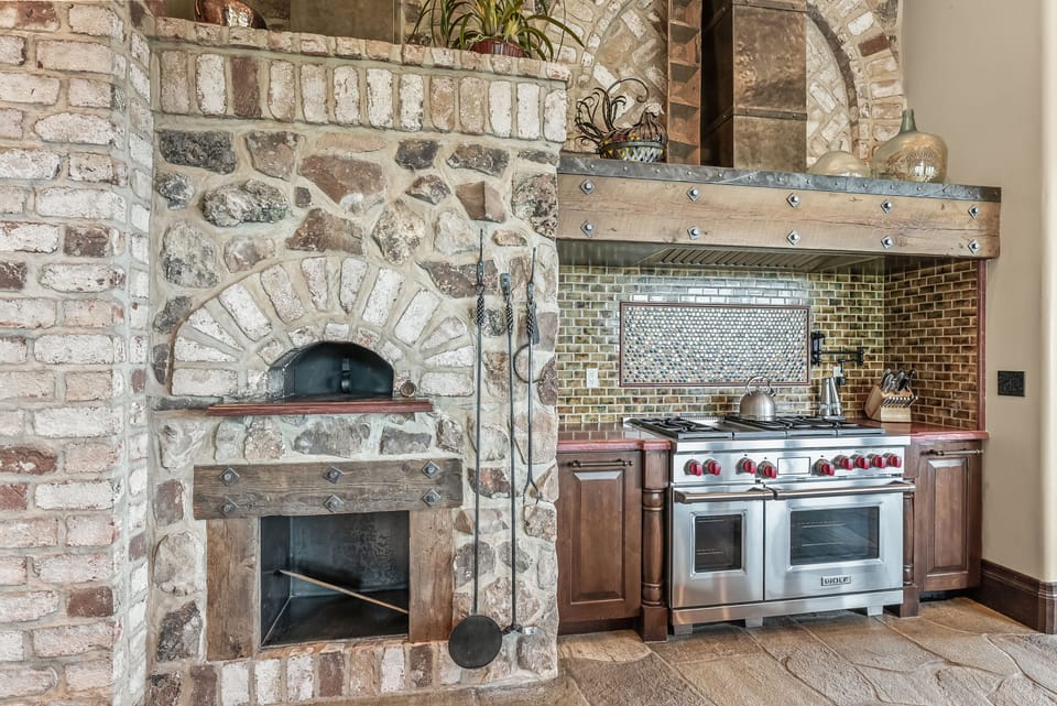 - Gourmet kitchen with stone pizza oven and rustic style  
- Professional-grade appliances for home-cooked meals  
- Brick and wood accents creating a warm atmosphere