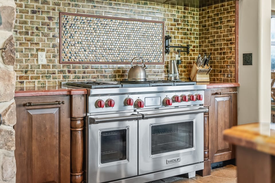 - Gourmet Wolf range with six burners and double oven  
- Tile backsplash and wood cabinetry highlight rustic charm  
- Fully equipped for memorable meals and cooking experiences