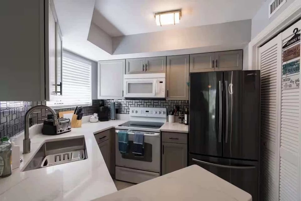 Kitchen with full-size appliances, subway tile backsplash, and a corner sink.