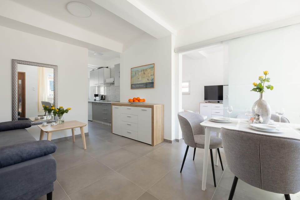 A modern, open-plan living room showcasing a well-lit area with elegant decor and a dining space in the background.
