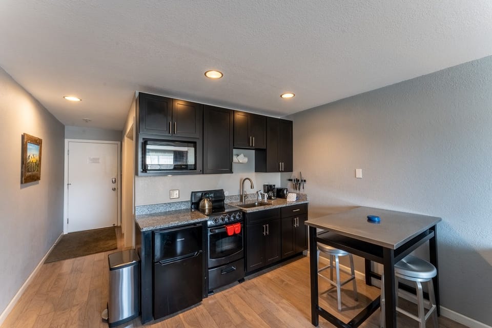 Your modern kitchenette features sleek dark cabinets, granite counters, and stainless steel appliances—perfect for preparing meals during your stay.