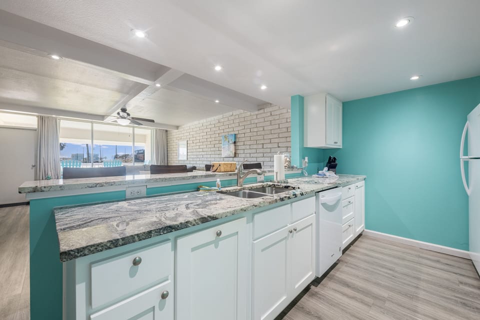 Cook memorable meals in your vibrant turquoise kitchen, featuring elegant granite counters and modern white cabinets with stunning views.