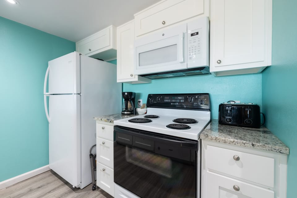 Your bright kitchen features full-size appliances and coastal-inspired turquoise walls, perfect for preparing meals with granite counters and modern conveniences.