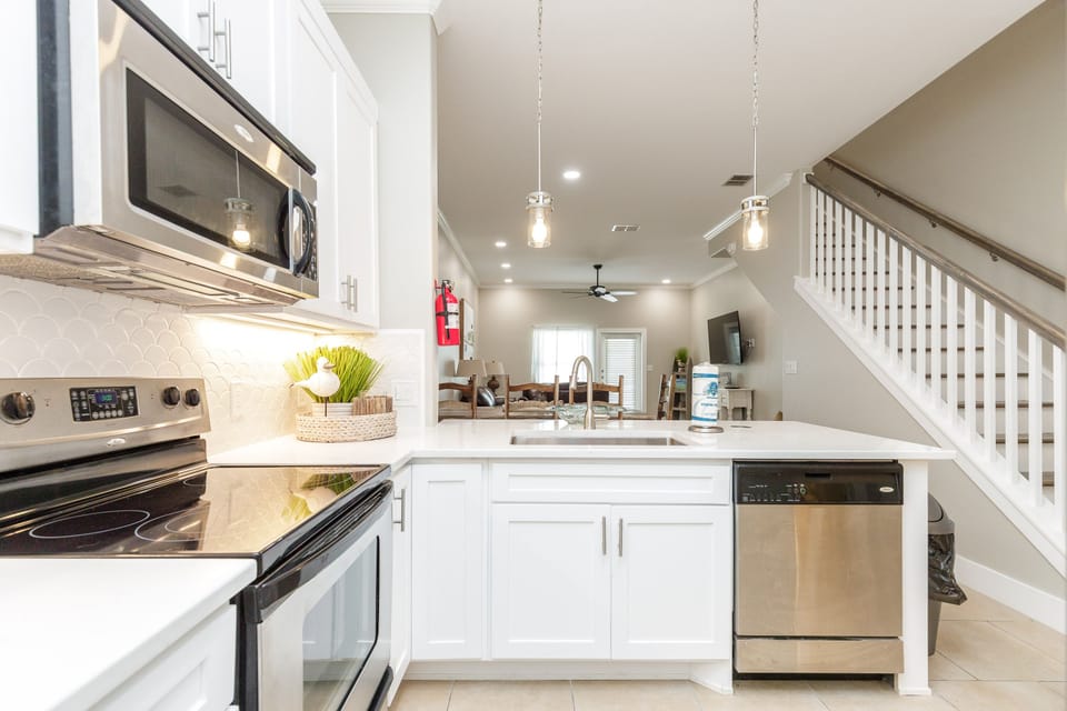 Your gleaming white kitchen features stainless steel appliances and pendant lighting, perfect for cooking memorable meals during your stay.