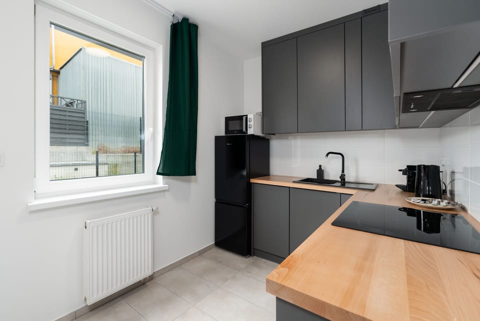 A modern kitchen with sleek dark cabinetry, wooden countertops, and fully equipped with appliances.
