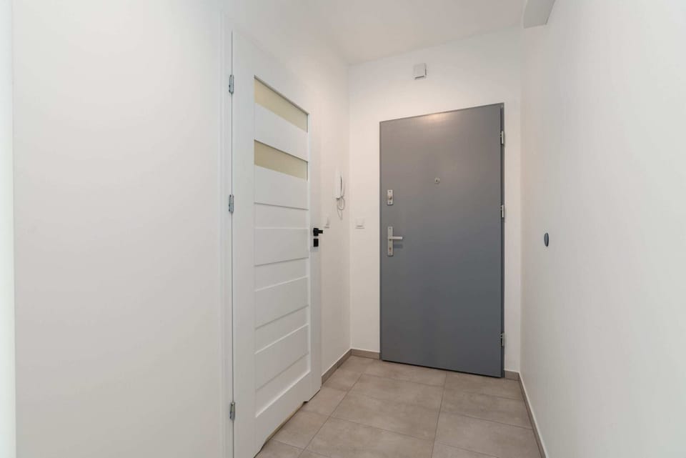 A spacious and well-lit hallway leading to the main door, highlighting its clean and neutral design.
