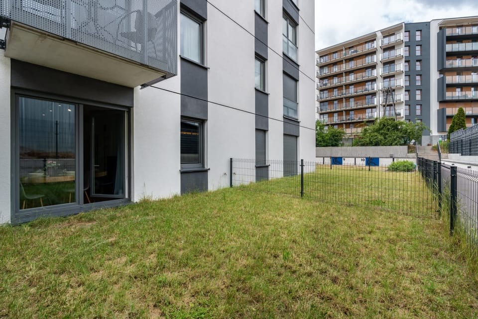 A green backyard space outside the building, fenced for privacy, ideal for outdoor activities.
