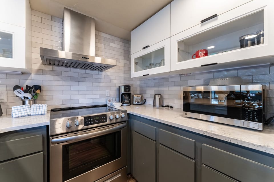 Your modern kitchen features premium stainless steel appliances, sleek white subway tile backsplash, and marble countertops perfect for creating memorable meals.