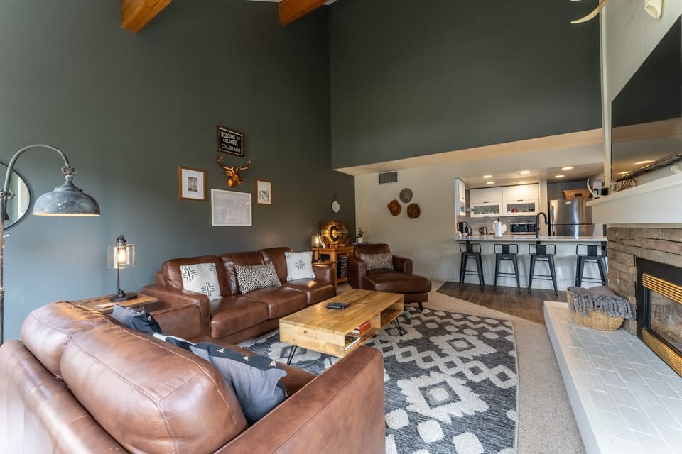 Relax in your spacious living room with rich leather seating, warm fireplace, and open kitchen—perfect for unwinding after mountain adventures.
