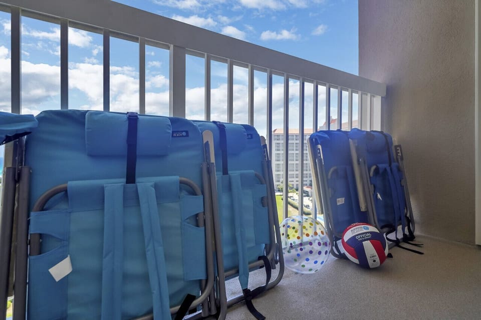 Beach-ready condo: Chairs, umbrella, toys.