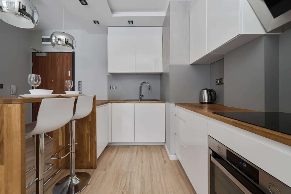 Stylish kitchen with an island and bar stools, featuring light wood and white tones.
