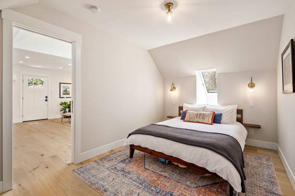 Layered bedding and a skylight-style window make this bedroom feel restful.