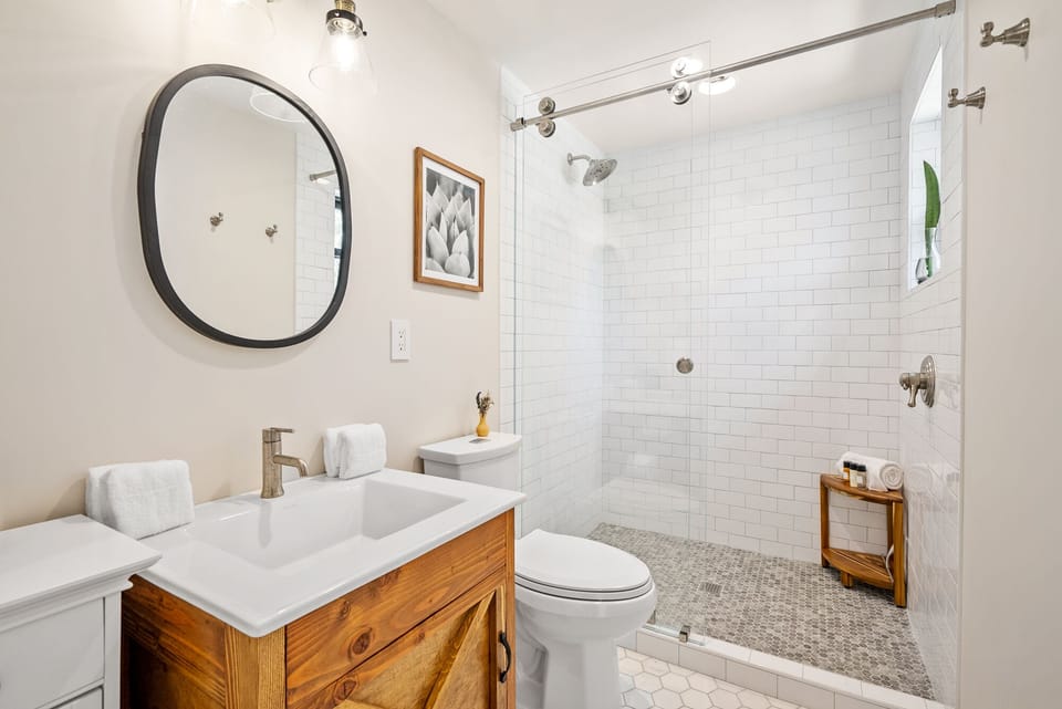 A tiled walk-in shower and wood vanity keep this full bathroom feeling fresh and simple.