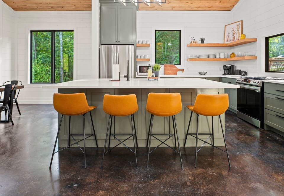 Gather around the stylish island with vibrant mustard stools for a casual breakfast or evening drinks in this modern kitchen.