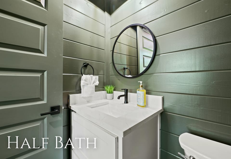 Stylish half bath pairs green walls with sleek, modern fixtures, offering a fresh and streamlined look.
