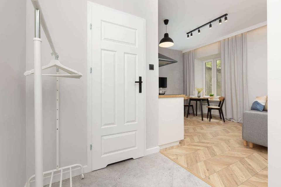 A hallway with clean white walls, stylish lighting, and a functional layout leading to other rooms.
