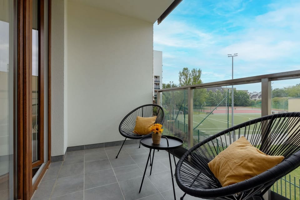 The balcony is furnished with a small table and chairs, creating a perfect spot to enjoy a morning coffee or relax outdoors. It offers a pleasant view of the surrounding area.