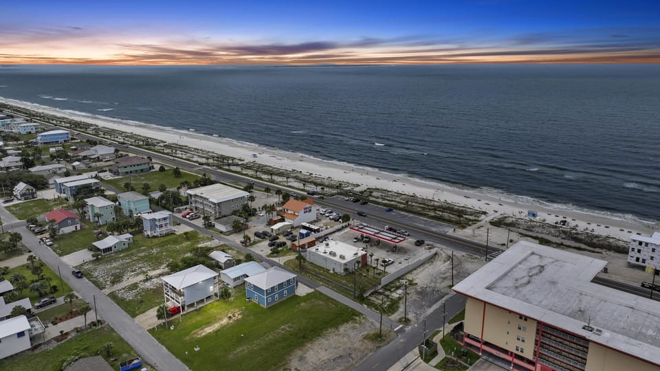 Aerial view of beachfront community featuring colorful coastal homes along pristine sandy shores at golden hour.