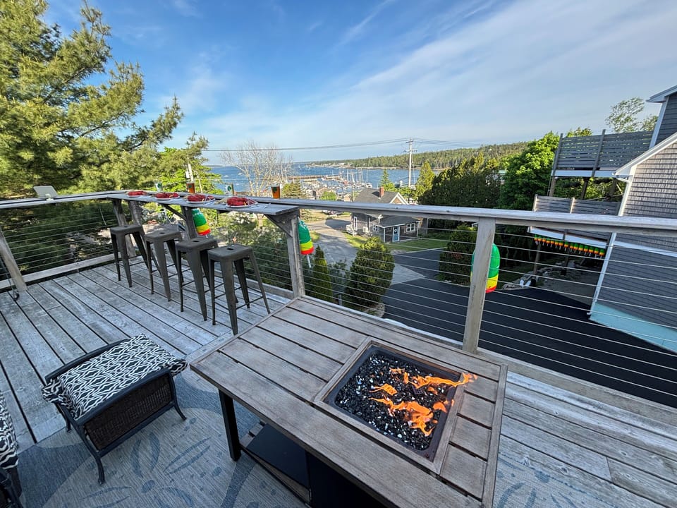 Gas firepit, deck furniture, and elevated dining railing overlooking the marina