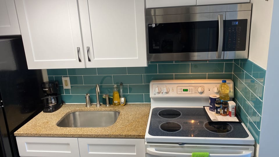 Full kitchen newly renovated with beach blue tiles, white cabinets, modern furnishing