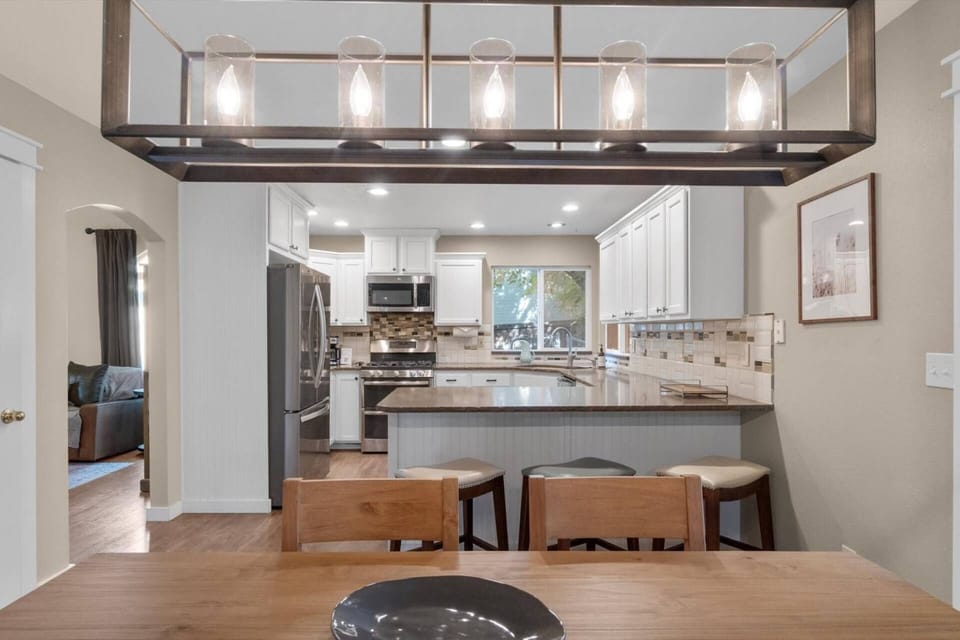 Spacious kitchen with granite countertops, stainless steel appliances, and peninsula with seating for three