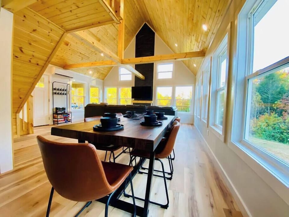Dining room table with seating for 6, abundant natural light with forest backdrop for privacy, and 55" TV with leather sectional