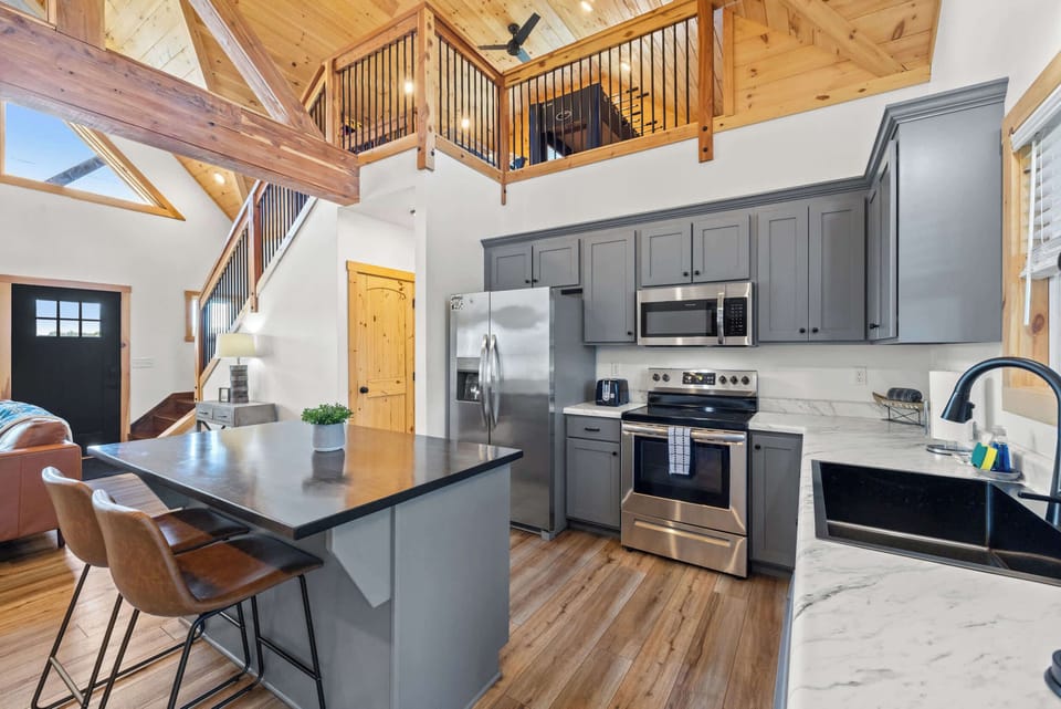 Modern kitchen with a spacious island and two stools, perfect for casual dining or chatting while you cook. Fully stocked with essentials, plus a full fridge, oven, and microwave—ready for family meals, morning coffee, and late-night snacks.