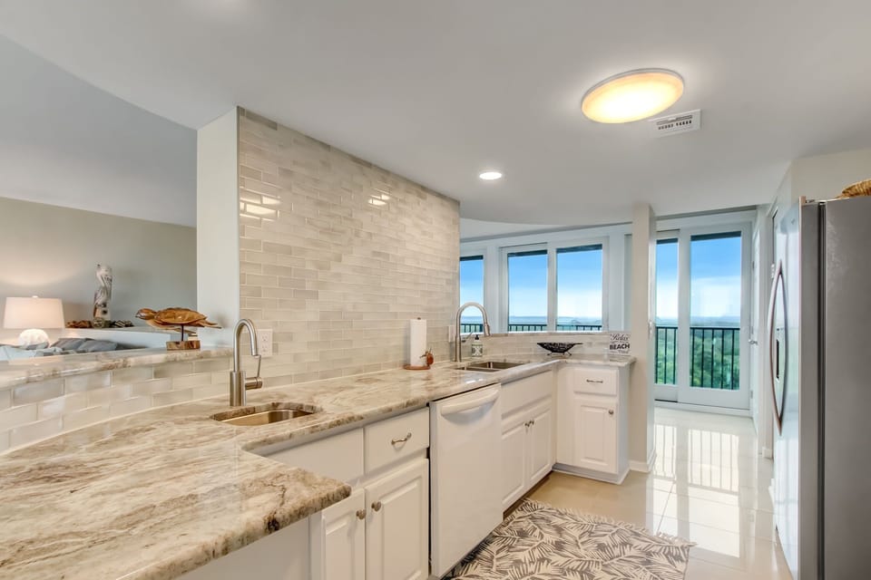 Updated Kitchen with a Marble Countertop, Stainless Steel Appliances, Tiled Backsplash, and Second Sink