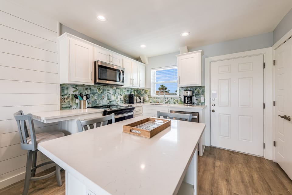 Your bright coastal kitchen features modern appliances and a charming island perfect for morning coffee or meal prep.