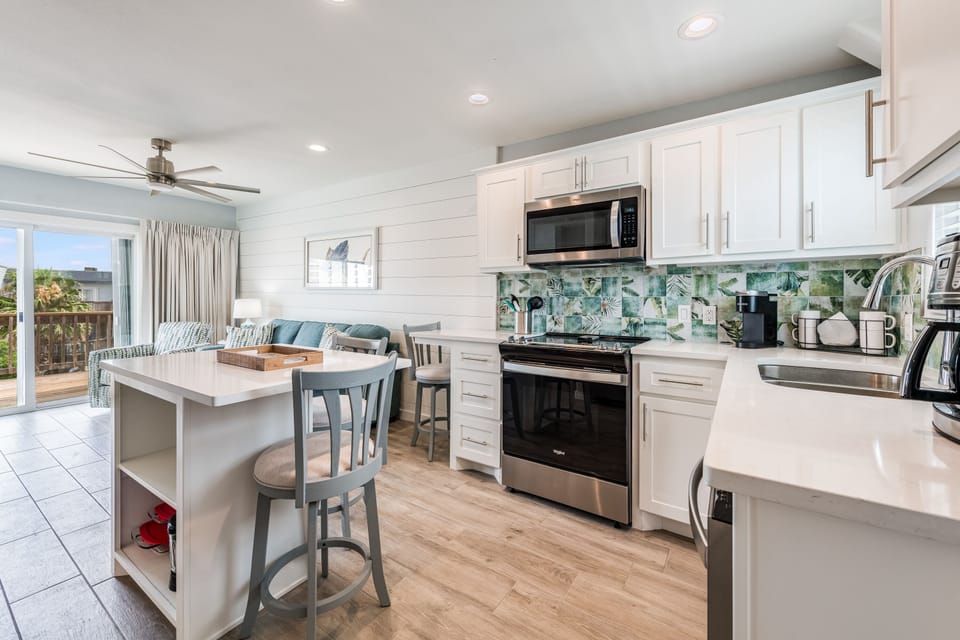 Your bright, open kitchen features modern appliances and coastal-inspired backsplash, perfect for preparing meals while staying connected to your vacation companions.