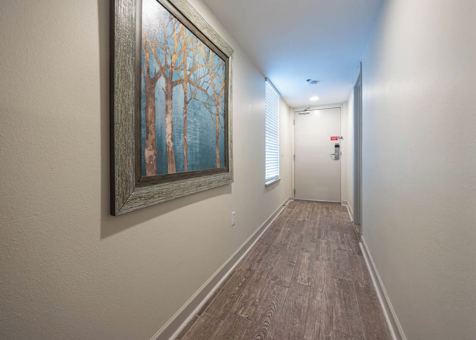 Welcoming hallway featuring a framed tree artwork and natural light streaming through a window, leading to the entrance door