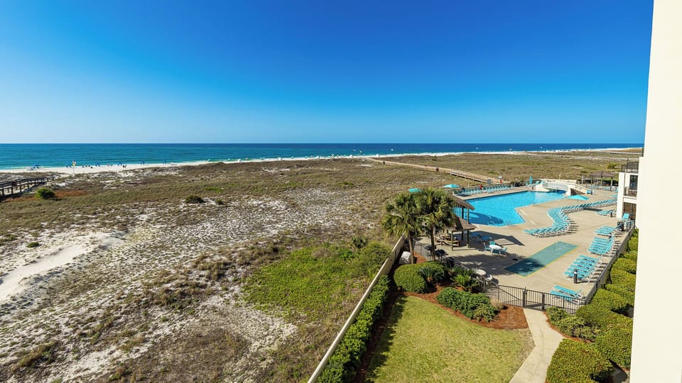Relax on your balcony, soaking in sunlit views of the coast and the refreshing pool area below