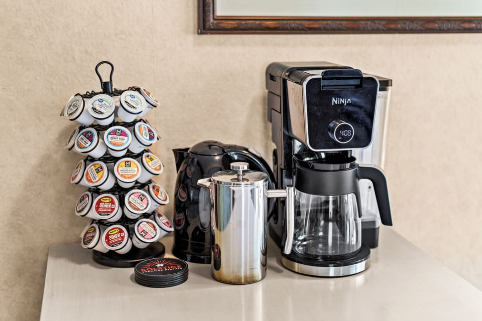 Coffee station is stocked with drip coffee maker, french press, and tea kettle.
