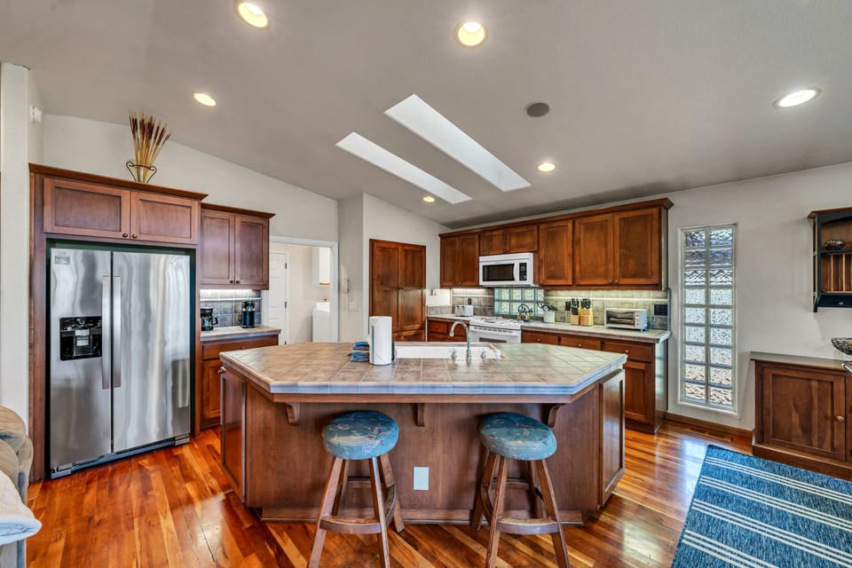 The spacious kitchen features a large kitchen island with 2 barstools, stainless steel appliances, and everything you need to cook a delicious meal for your group.
