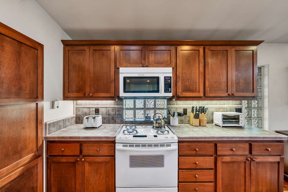 The spacious kitchen features a large kitchen island with 2 barstools, stainless steel appliances, and everything you need to cook a delicious meal for your group.