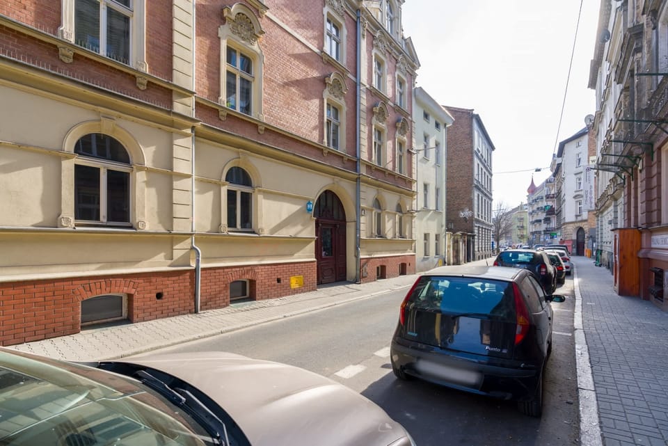 A view of the quiet street outside the building, lined with historic architecture and parked cars.
