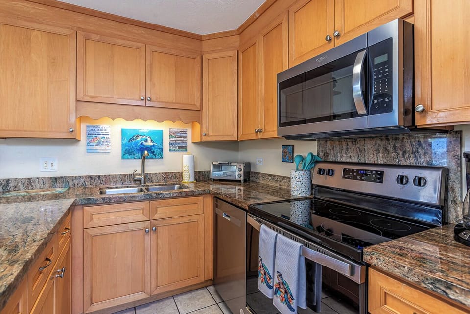 Step into your vacation kitchen featuring warm wood cabinetry, granite counters, and stainless steel appliances ready for easy meal prep.